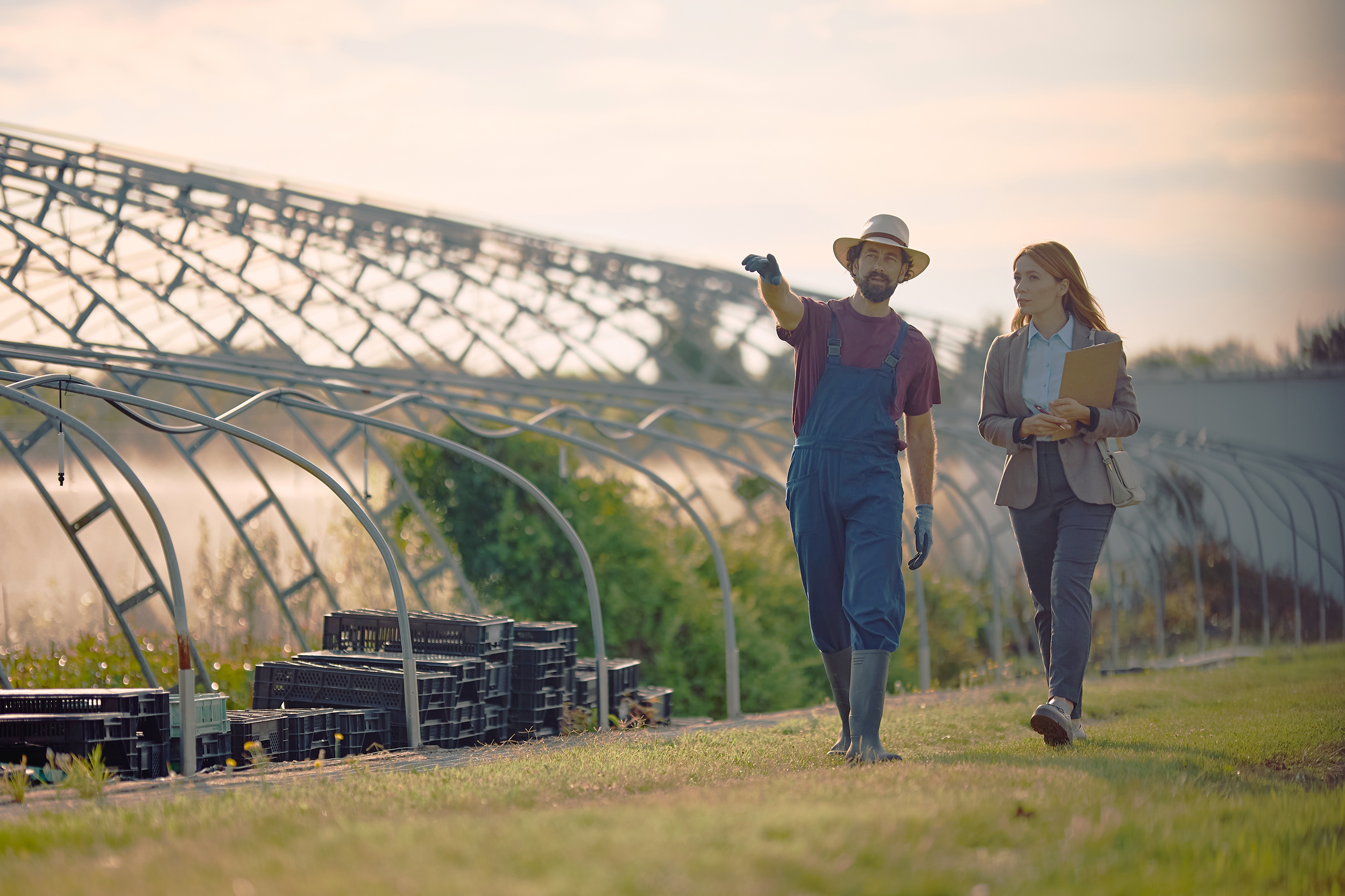 Farm,Worker,And,Businesswoman,Talking,While,Walking,Through,His,Property.