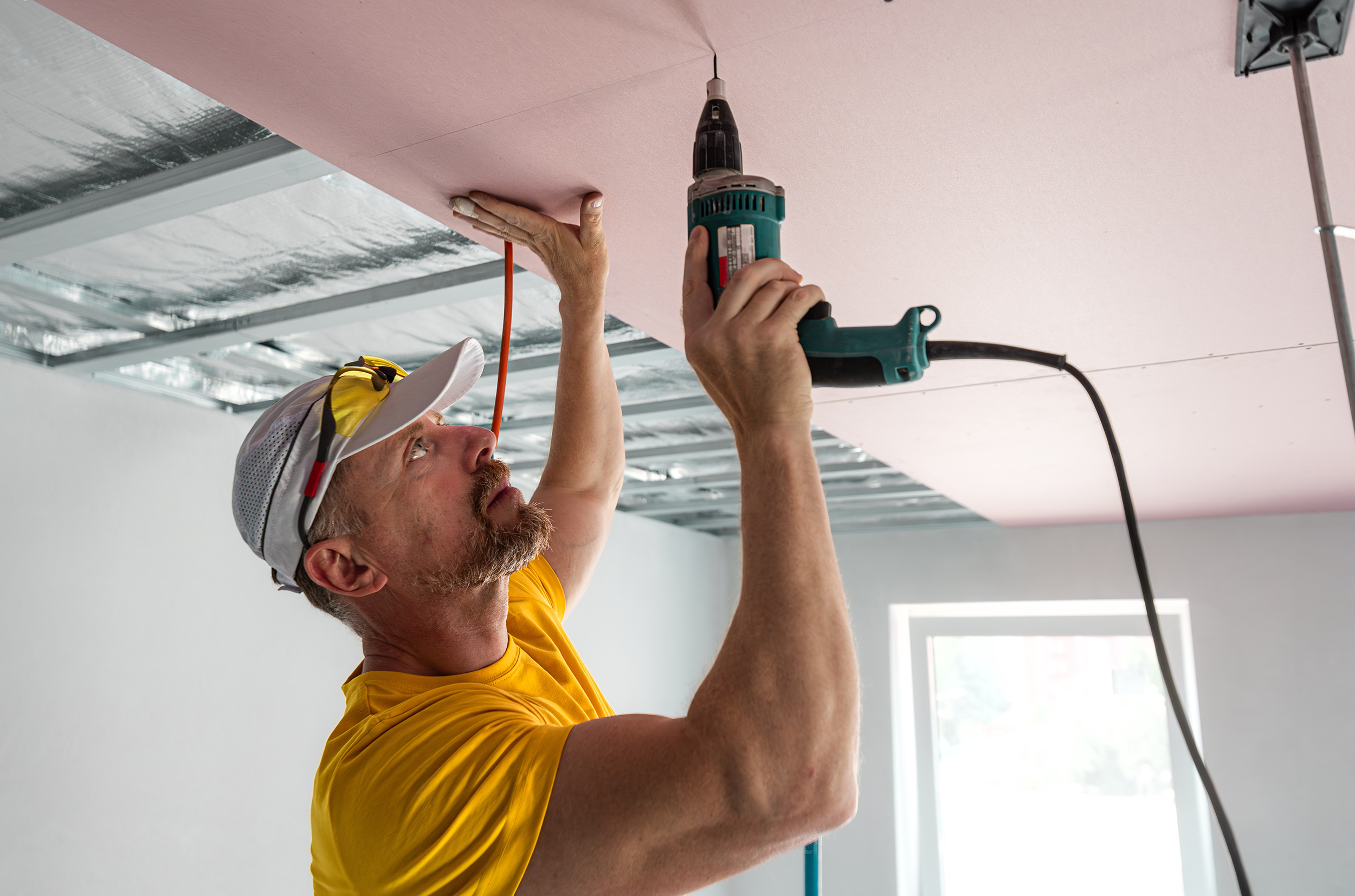 The,Worker,Screwing,Plasterboard,To,The,Ceiling.,He,Is,Using
